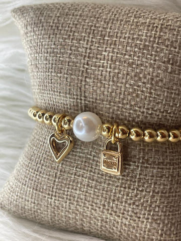 Tucco elastic bracelet with heart, padlock and pearl charm. Gold plated. Zamak